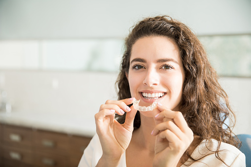 Woman holding Invisalign clear aligner tray from SmileCOS Dentistry in Colorado Springs.
